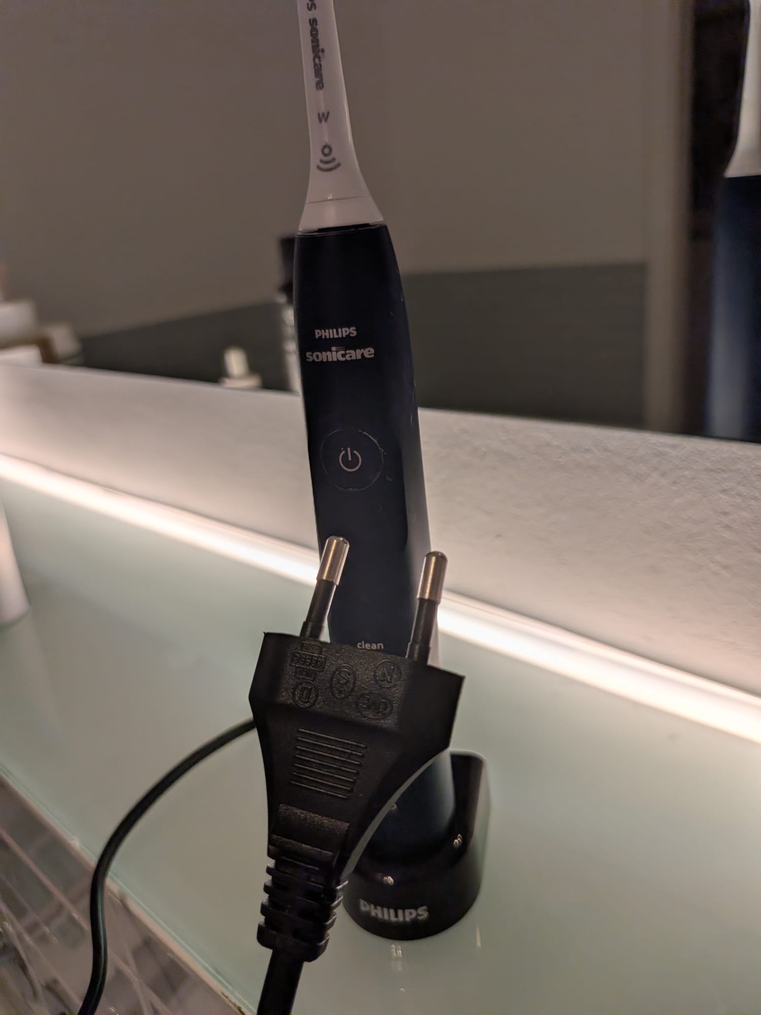 The Philips Sonicare toothbrush next to an old-school charger with a real wall plug